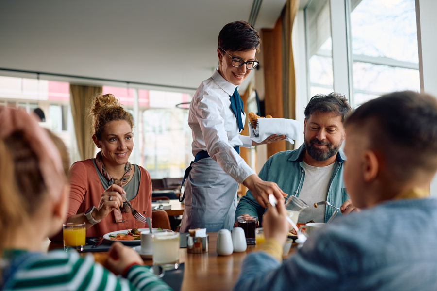 happy-hotel-waitress-serving-family-who-is-having-2026-03-17-07-06-27-utc.jpg